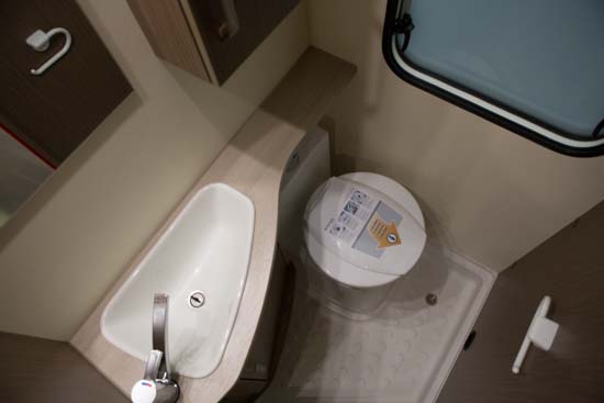 Bagerst i Knaus Lifestyle 550 er der et badeværelse med brusebund, håndvask, nogle skabe og toilet