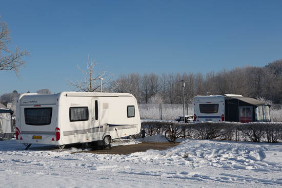 To af komfortpladserne på Frigård Camping. Man kan frit vælge om man vil stille campingvognen på stenbelægningen, eller som her bruge den som terrasse