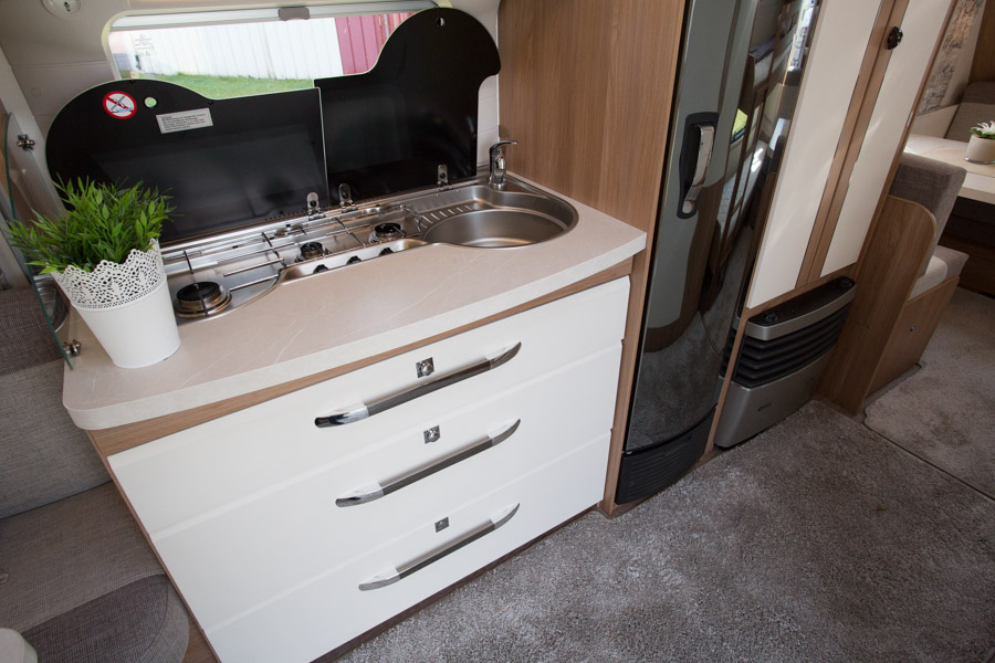 I midten af Hobby De Luxe 515 UHK er der køkken med Slimtower køleskab på 150 liter, komfur, vask og skuffer og skabe til køkkengrej og service.